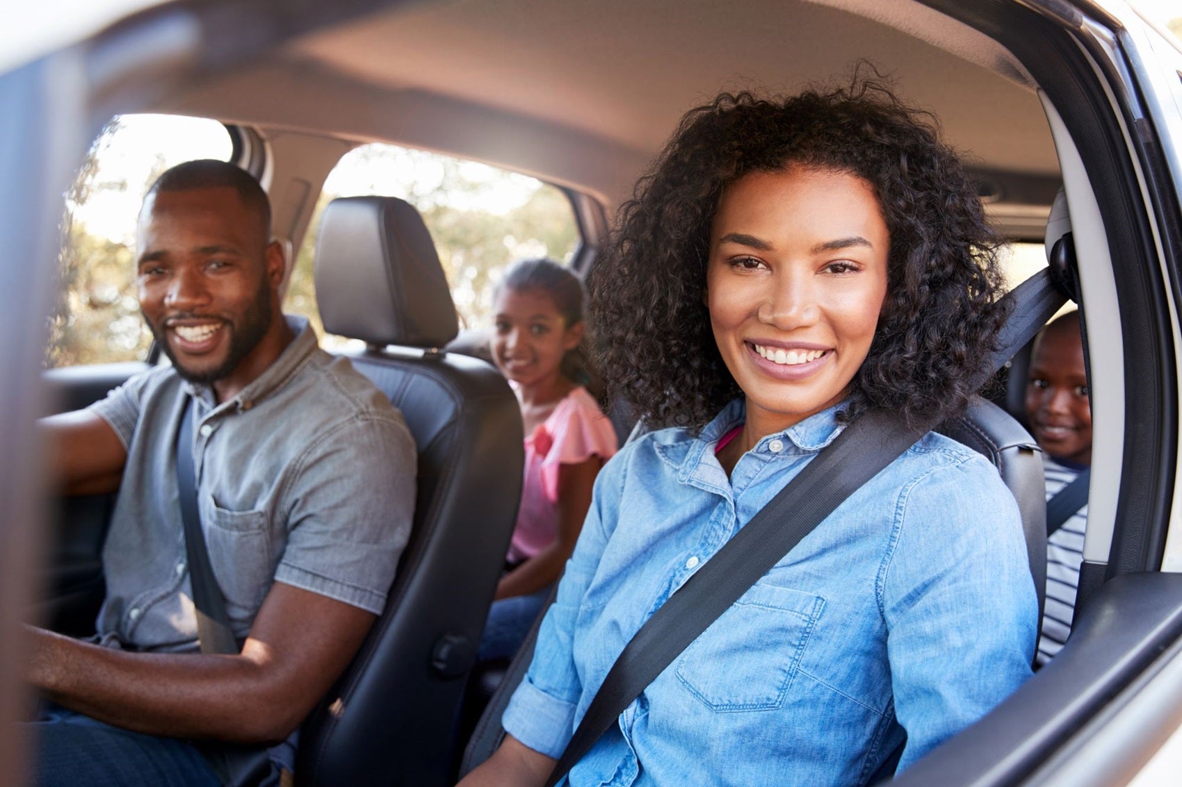 Family smiling in their Ford vehicle on a trip