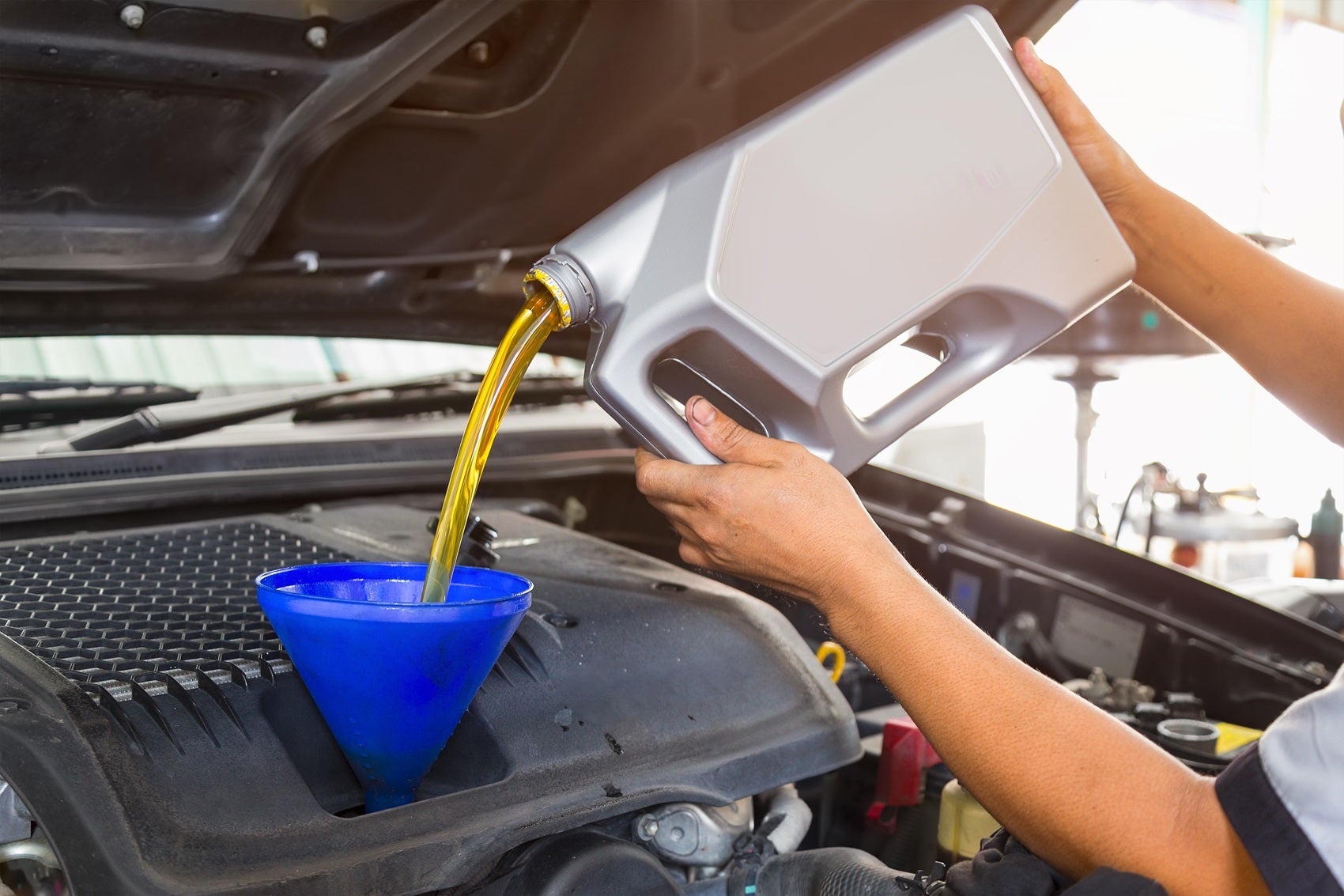 Ford Certified Technician using a filter to pour oil during oil change maintenance